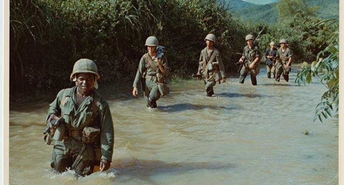 Soldiers march through the waters of Vietnam in Ken Burns & Lynn Novick's The Vietnam War. Photo Credit: National Archives and Records Administration S7535 -
