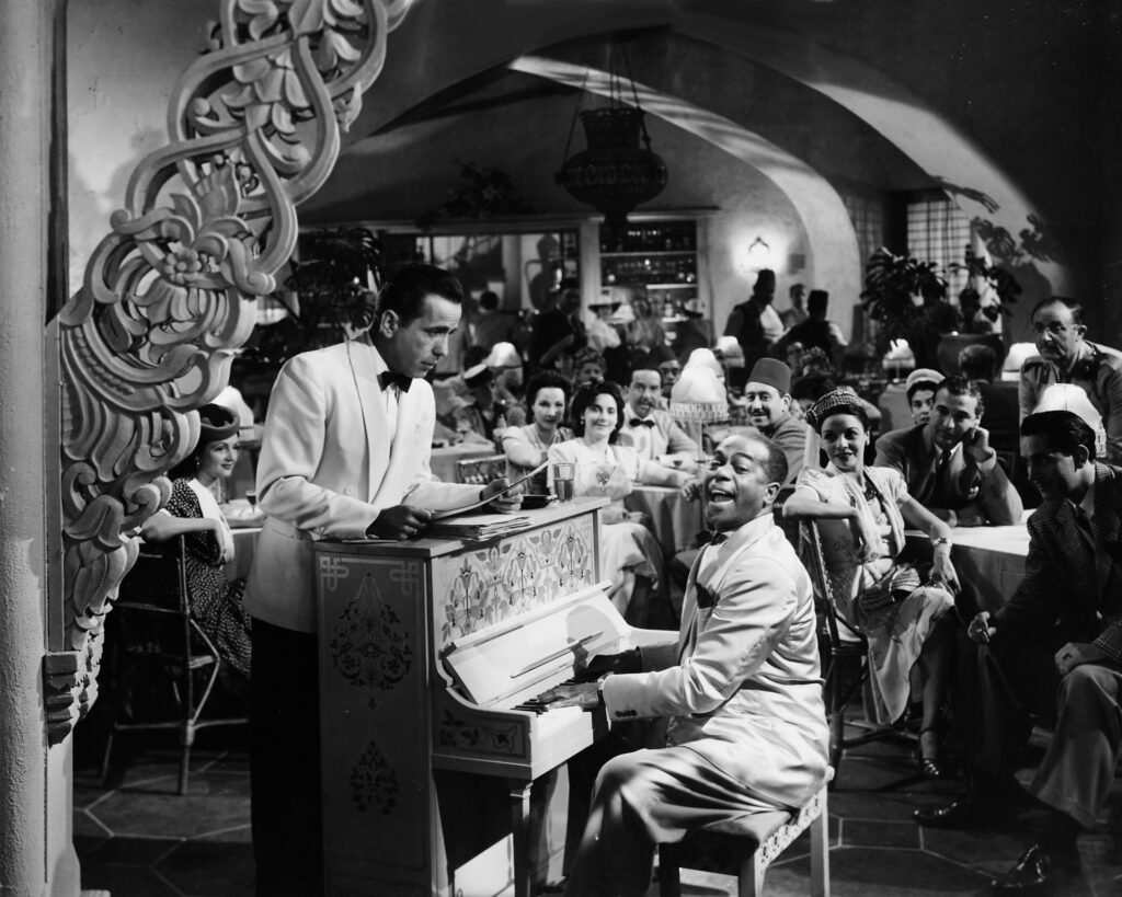 Left to right: American actor and singer Dooley Wilson (1894 - 1953) accompanies himself on the piano as Humphrey Bogart (1899 - 1957) looks on in a scene from 'Casablanca', directed by Michael Curtiz, 1942. (Photo by Silver Screen Collection/Hulton Archive/Getty Images)